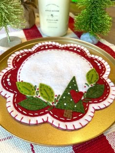 a christmas table setting with a candle and some decorations on the table cloth, along with a bottle of milk