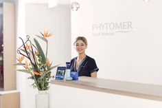 a woman standing at the front desk of a phytomer store