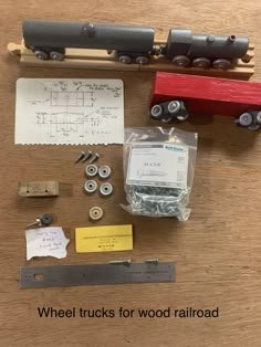 a wooden table topped with lots of different types of toy train cars and parts on top of it