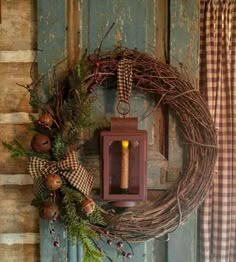 a wreath with a candle on it hanging from the side of a wooden door next to a window