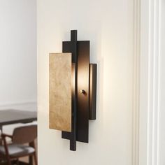 a wall light mounted on the side of a white wall next to a dining room table