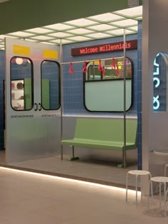 an empty bench in front of a blue and white subway station with the doors open