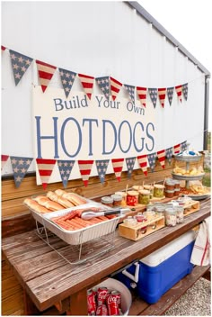 hot dogs and buns on a picnic table with bun flags in the background at a patriotic party