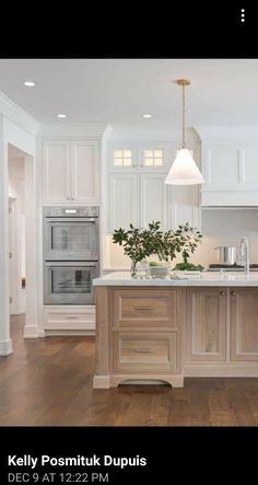 a large kitchen with white cabinets and wood floors