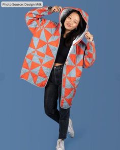 a woman in an orange and blue jacket posing for the camera with her hands on her hips