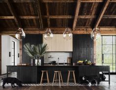 an open kitchen with wooden floors and black counter tops, along with two stools