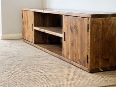 a wooden entertainment center sitting on top of a carpeted floor next to a wall