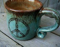 a coffee cup with peace sign painted on the outside and inside is sitting on a wooden table