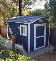 a blue and white shed sitting next to a tree