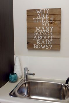 a kitchen sink with a wooden sign above it that says why they are so many song's about rain bows?