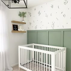 a baby's room with a white crib and green wallpaper