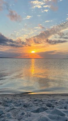 the sun is setting over the water at the beach