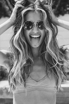 a woman with her hair in the air and sunglasses on, making a funny face