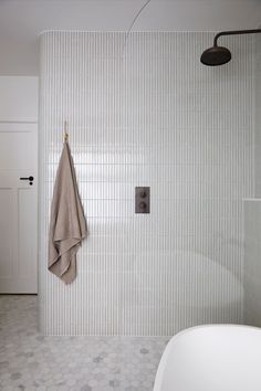 a bath room with a tub and a towel hanging on the shower headrests