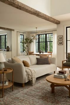 a living room filled with furniture and windows next to a wooden coffee table on top of a rug