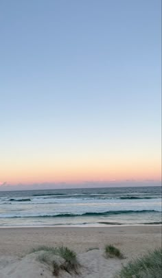 an empty bench on the beach at sunset