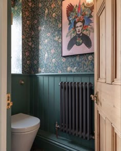 the bathroom is decorated in green and blue with an art print on the wall above the toilet