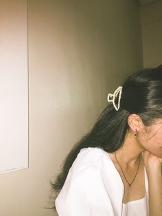 a woman is brushing her hair with a comb and looking in the mirror while wearing a white shirt