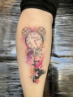 a tattoo on the leg of a woman with a clock and key in her hand