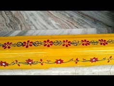 a yellow vase sitting on top of a marble floor next to a red flowered design