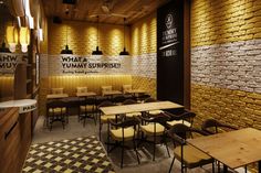 an empty restaurant with yellow brick walls and wooden tables set up for people to eat