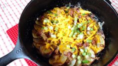 a skillet filled with potatoes and cheese on top of a table