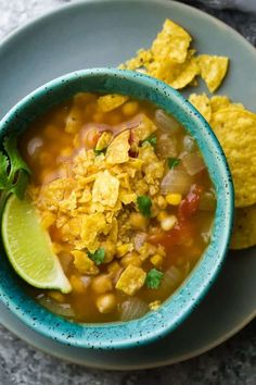 a blue bowl filled with soup next to tortilla chips on a gray plate