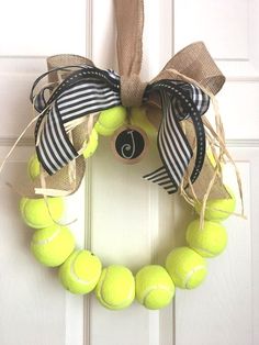 a tennis ball wreath is hanging on the front door with black and white striped ribbon