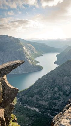 a person standing on the edge of a cliff overlooking a body of water and mountains