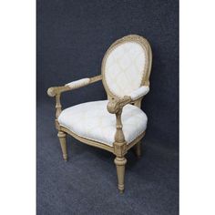 an antique chair with white upholstered fabric