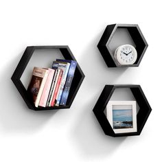 three black hexagonal shelves with books on each shelf and a clock mounted to the wall