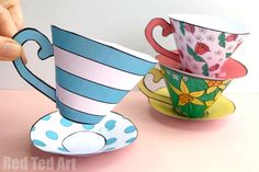 two cups are sitting next to each other on a table with one being held up by a hand