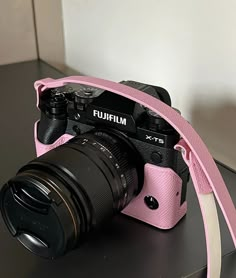 a pink camera sitting on top of a table next to a black and white wall