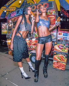 two women standing next to each other in front of a food cart with hot dogs on it