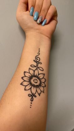 a woman's arm with a black and white flower tattoo on the left wrist