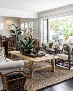 a living room filled with lots of furniture and plants on top of a wooden table