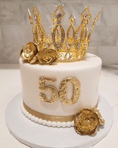 a white cake with gold decorations and a crown on top