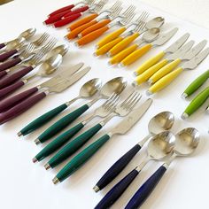 a table topped with lots of different colored spoons and forkes next to each other