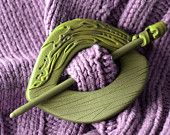 a green crochet hook with purple yarn in the center on a purple sweater