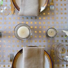 the table is set with plates, silverware and candles