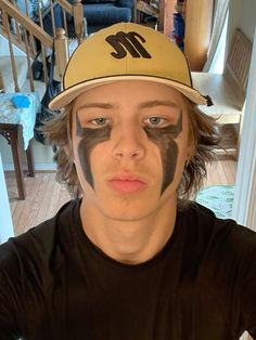 a young man with his face painted like a baseball cap and the word m on it