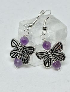 Add some whimsy to your life! Silver plate butterflies and purple amethyst beads are featured in these semi precious stone earrings. Earrings drop from silver plate earwires. Amethyst is a February birthstone. These would make a great birthday gift. Earrings come on earring card with clear silicone safety backs. Comes in a box with bow appropriate for gifting.  Drop length: .75 inches ► CUSTOM ITEMS AVAILABLE ◄ Need a different length? Like this style, but want it in a different color? Looking for more than one? Contact me with your request and I'll see what I can do! Return to my Shop www.etsy.com/shop/ItsMyCreativeNature  All jewelry items are handmade by me in my little home studio in north central Texas. Amethyst Butterfly, Healing Stones Jewelry, Earring Card, Earrings Purple, February Birthstone, Amethyst Beads, Earrings Drop, February Birth Stone, Butterfly Earrings