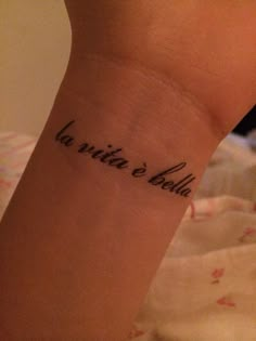 a woman with a tattoo on her arm that says la vita e bellaa in cursive writing