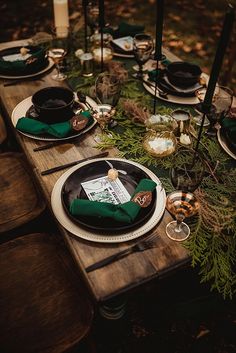 the table is set with black plates, green napkins and place settings for dinner