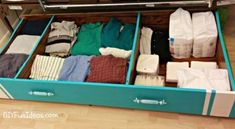 an open drawer filled with clothes on top of a wooden floor