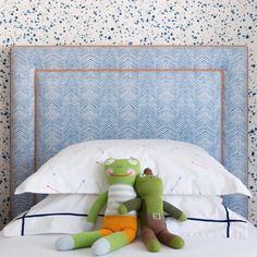 two stuffed animals sitting on top of a bed in front of a blue headboard