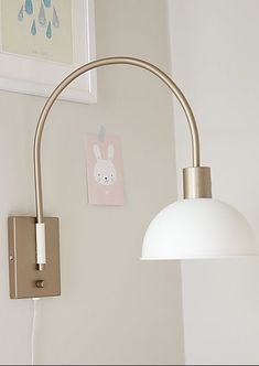 a white lamp is on the wall next to a framed picture and a light fixture