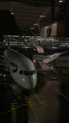 an airplane is parked on the tarmac at night with other planes in the background