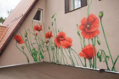 a mural on the side of a building with red flowers painted on it