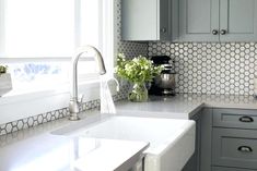 a kitchen with gray cabinets and white counter tops, along with a sink in the center